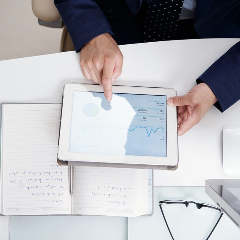 Business executive analyzing financial report on tablet computer, view from above